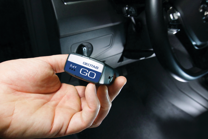 Mano sosteniendo un dispositivo telemático (Go Device) de pequeño tamaño listo para conectar al puerto OBD II de un vehículo.